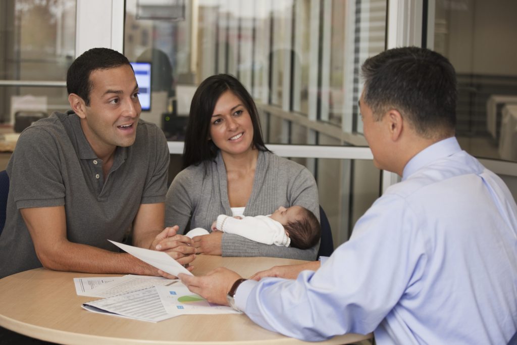 Hispanic couple with baby talking to financial advisor
