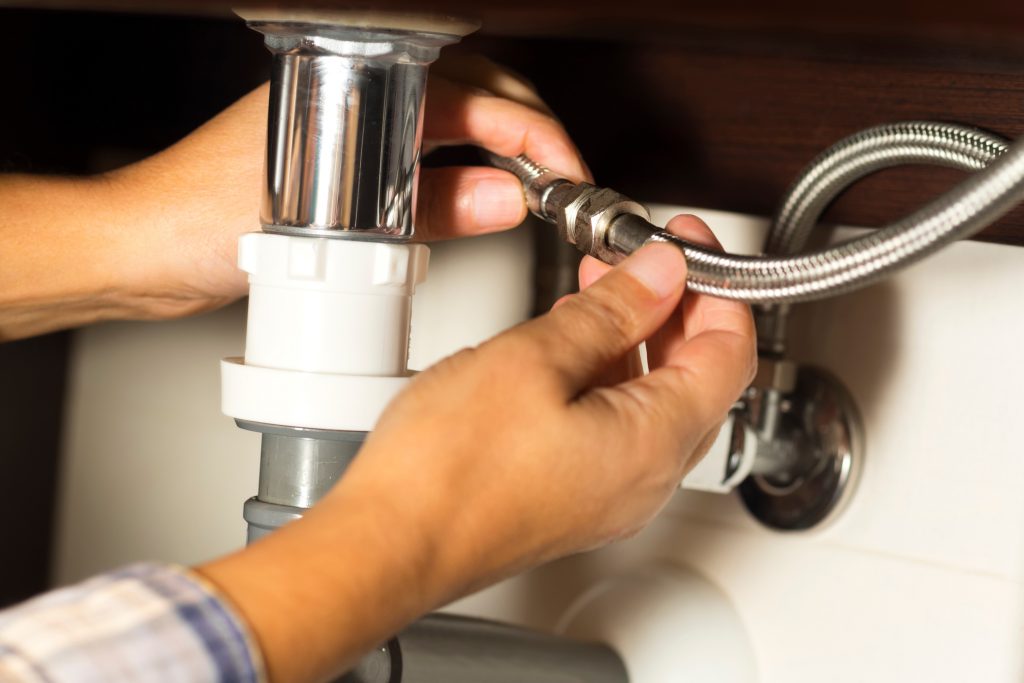 Cropped Hands Of Woman Repairing Bathroom Sink